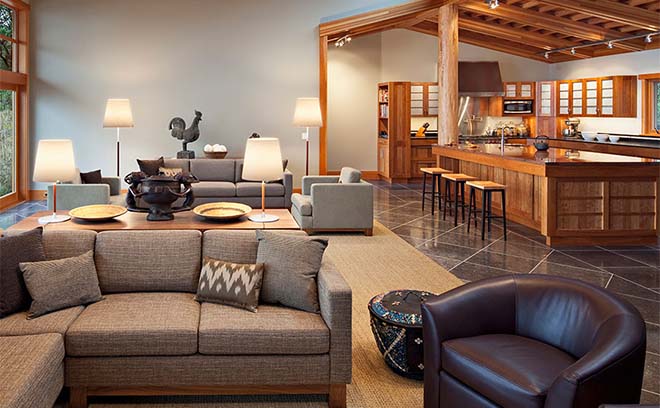 Modern living room with cozy seating, warm wood accents, and an open kitchen. Soft lighting enhances the inviting atmosphere.