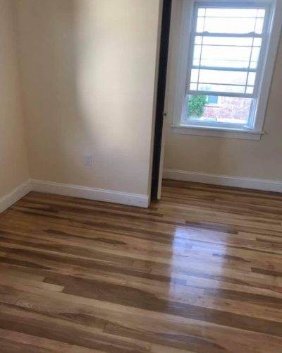 A room featuring hardwood floors and a large window allowing natural light to enter.