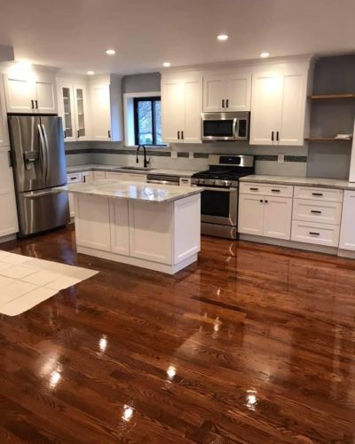 A modern kitchen featuring hardwood floors and sleek white cabinets, creating a bright and inviting atmosphere.
