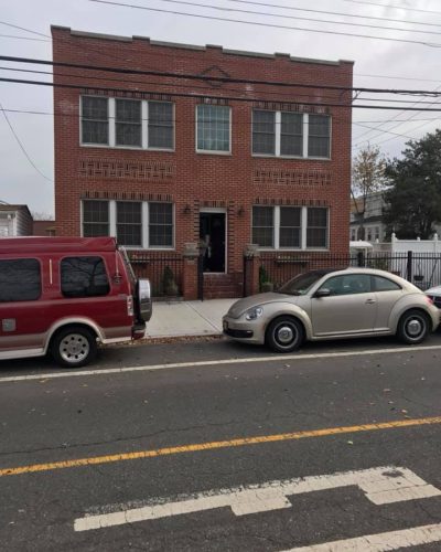 Two vans parked in front of a red brick building, showcasing a clear view of the vehicles and the structure behind them.