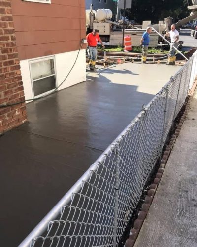 Concrete being poured at a construction site in New Jersey, with workers and machinery visible in the background.