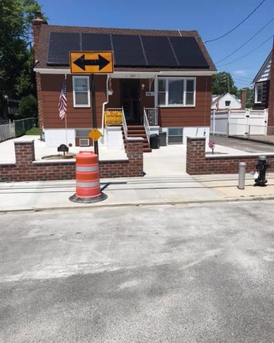 A house featuring a solar panel on the roof and a "no parking" sign in front of it.