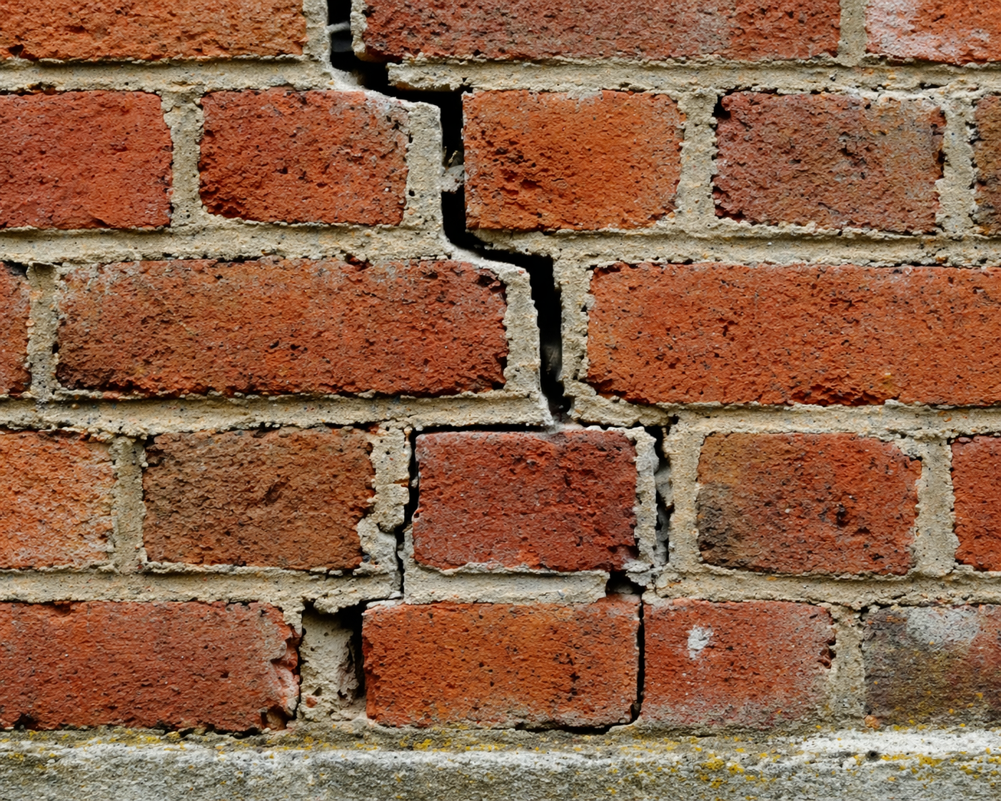 Masonry repair needed for cracked brick wall with damaged mortar joints.